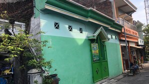 A green building with a green door, a small window, and a signboard. - Hotel O Homestay Pak To Syariah (Surabaya)