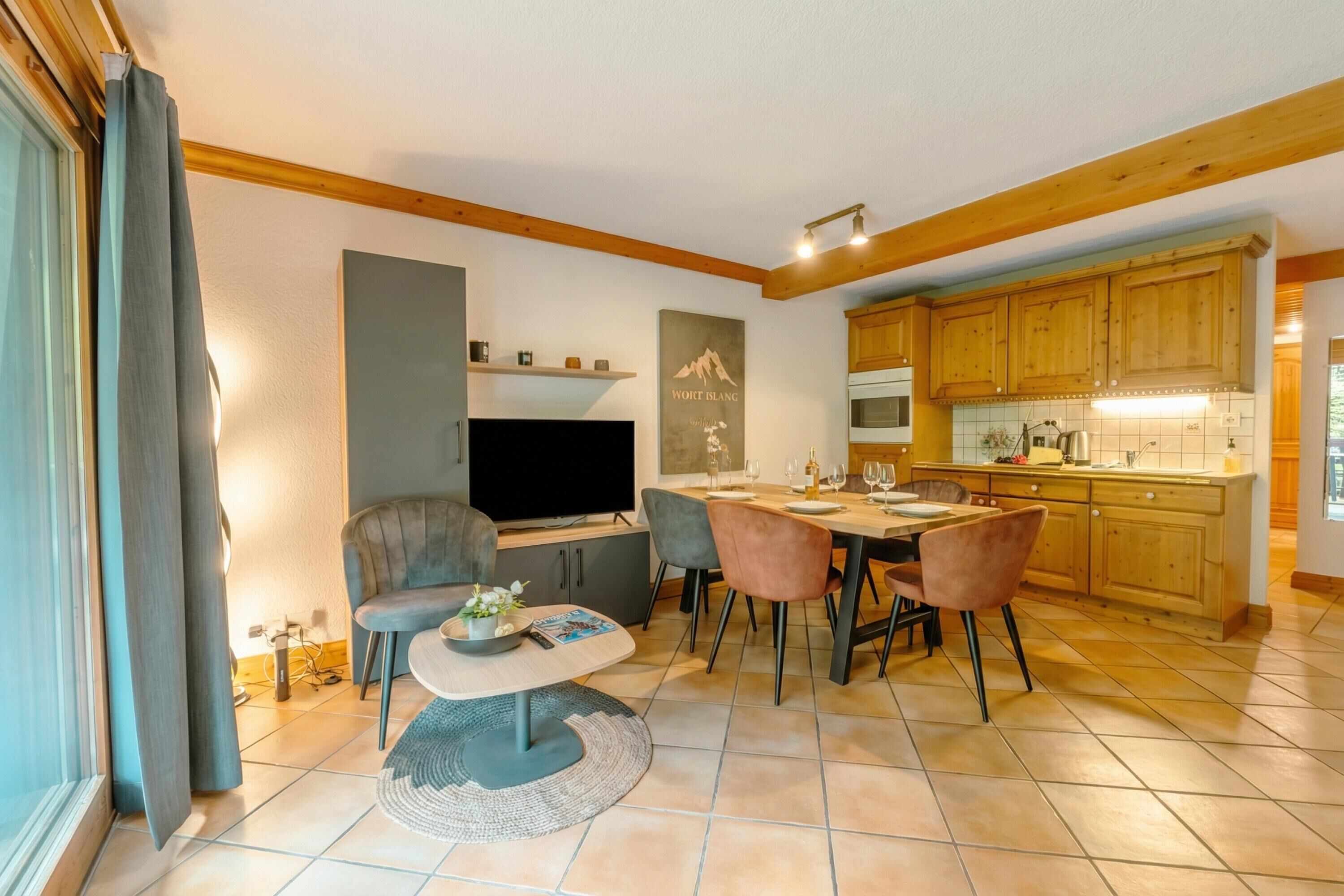 A modern living room with a TV, seating, and a dining area with a table and chairs.