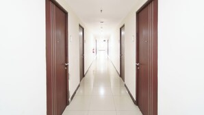 A long, narrow hallway with wooden doors on both sides and a tiled floor.