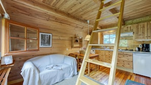 A cozy cabin with a bed, a ladder, a kitchen area, and a window with a view of trees. - Mazot Mer de Glace near Chamonix w/ Private Garden, Deck & Views, Chamonix, France (Chamonix)