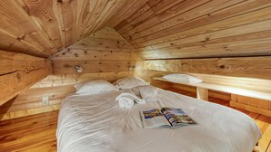 A wooden cabin room with a bed, pillows, and a magazine on the bed. - Mazot Mer de Glace near Chamonix w/ Private Garden, Deck & Views, Chamonix, France (Chamonix)