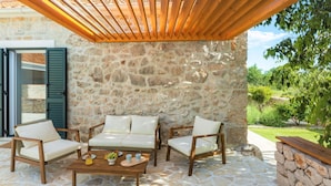 A stone patio with outdoor furniture, a wooden pergola, and a stone wall. - Villa di Perla by Interhome (Primošten)