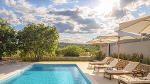 A swimming pool with lounge chairs and umbrellas, surrounded by stone walls and greenery. - Villa di Perla by Interhome (Primošten)