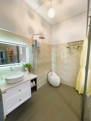 Une salle de bain moderne avec un grand miroir, un lavabo, une douche et des toilettes.
