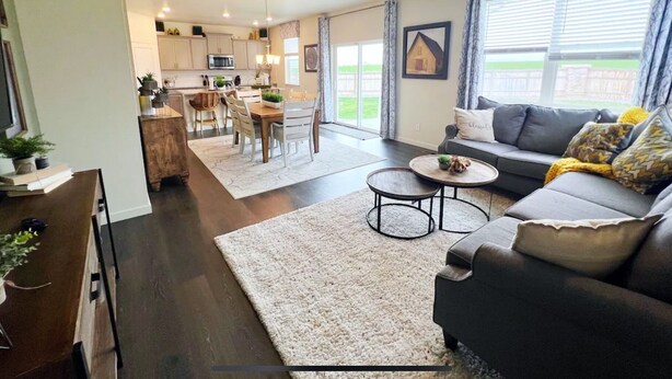 Ein modernes Wohnzimmer mit grauem Sofa, Couchtisch und Essbereich mit Holztisch und Stühlen.