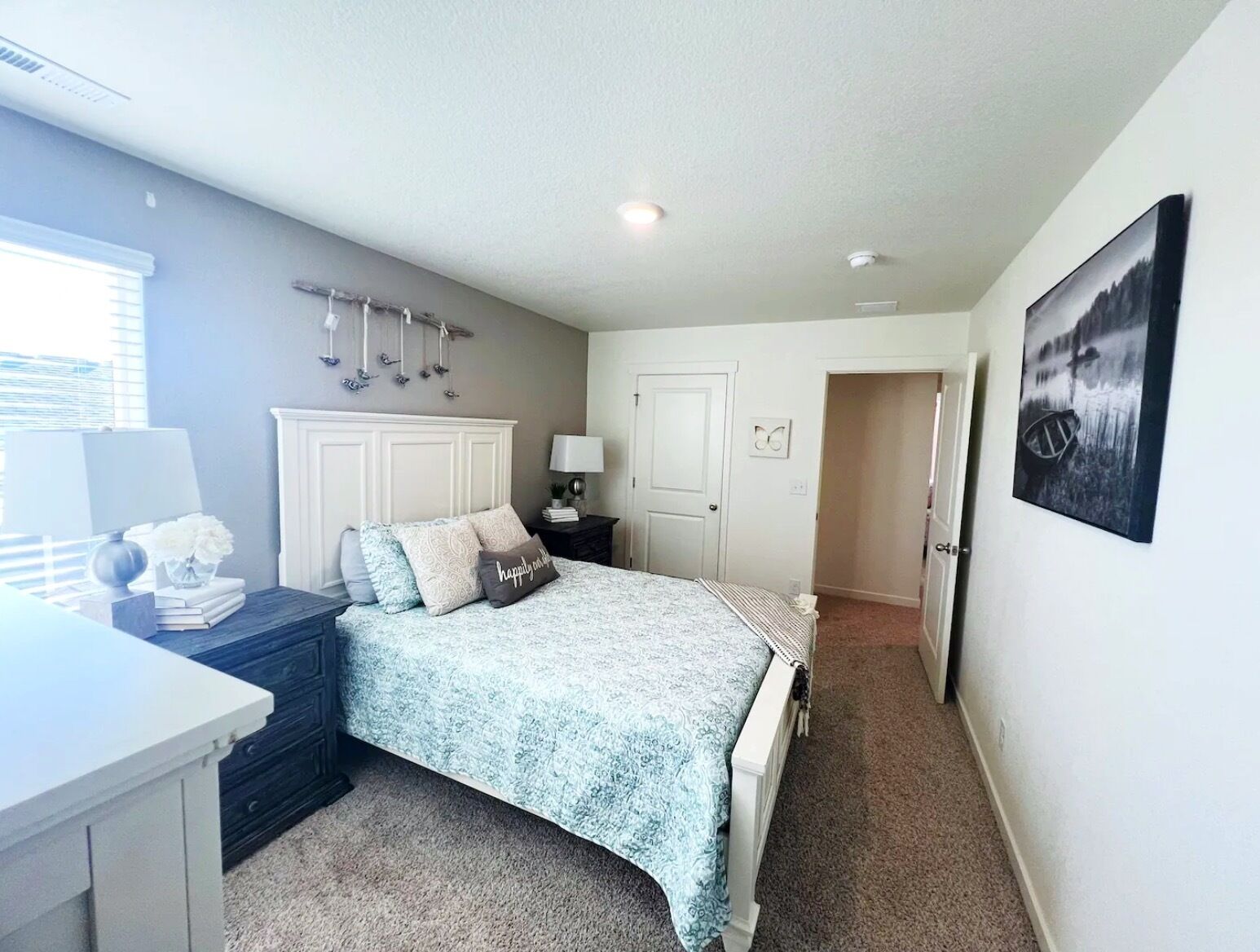 A bedroom with a bed, bedside table, lamp, and a painting on the wall.