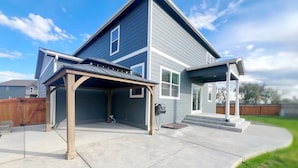Ein zweistöckiges Haus mit überdachter Terrasse und Garage.