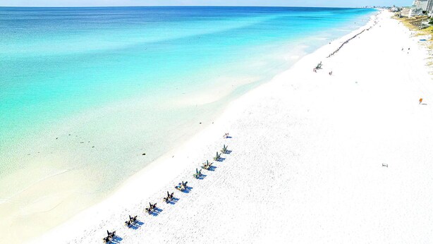 Ein Strand mit einer Reihe von Liegestühlen und Sonnenschirmen entlang der Küste.