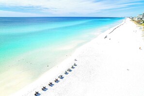 A beach with a row of beach chairs and umbrellas along the shoreline.