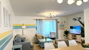 Ein modernes Wohnzimmer mit einer Couch, einem Couchtisch, einem Fernseher und einem Essbereich.