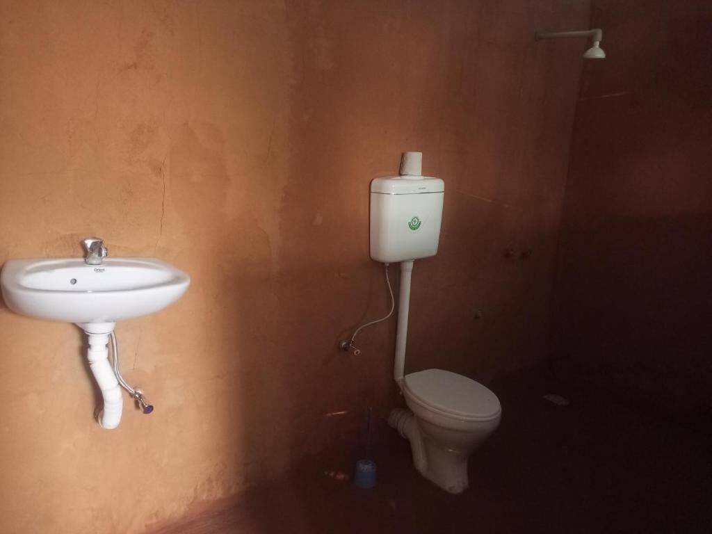 A bathroom with a white sink, toilet, and a wall-mounted toilet paper holder.
