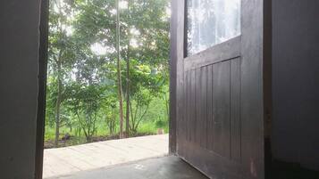 A doorway leading to a wooden deck with a view of a lush garden and trees.