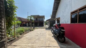 Un estrecho sendero de concreto que lleva a un edificio con una pared roja y una motocicleta estacionada.