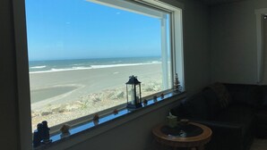 Ein Zimmer mit großem Fenster und Blick auf einen Strand.