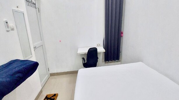 Una habitación pequeña y sencilla con cama, escritorio, silla y puerta.