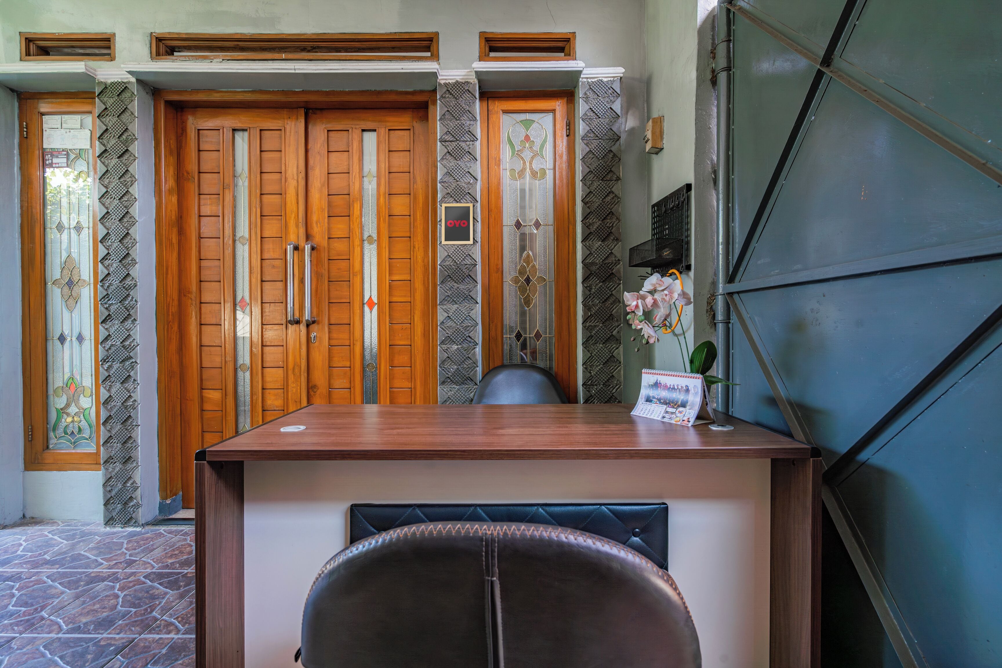 A reception desk with a wooden finish, a black leather chair, and a framed sign above the desk.