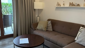 Een moderne woonkamer met een bank, een ronde salontafel en een lamp.