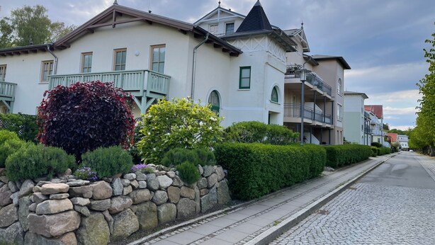 Un edificio residencial con pared de piedra, balcón y calle adoquinada.