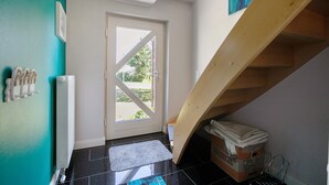 Une pièce avec une porte, un radiateur, un escalier en bois et un tapis.