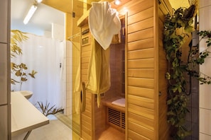 Un sauna en bois avec un banc, un porte-serviettes et une plante fixée au mur.
