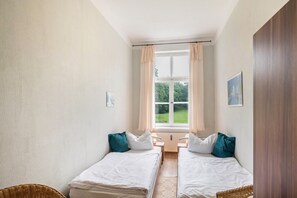 A room with two beds, a window with curtains, a small table, and a picture on the wall. - Apartment 'Ferienwohnung 8' with Shared Terrace and Shared Garden (Krakow am See)
