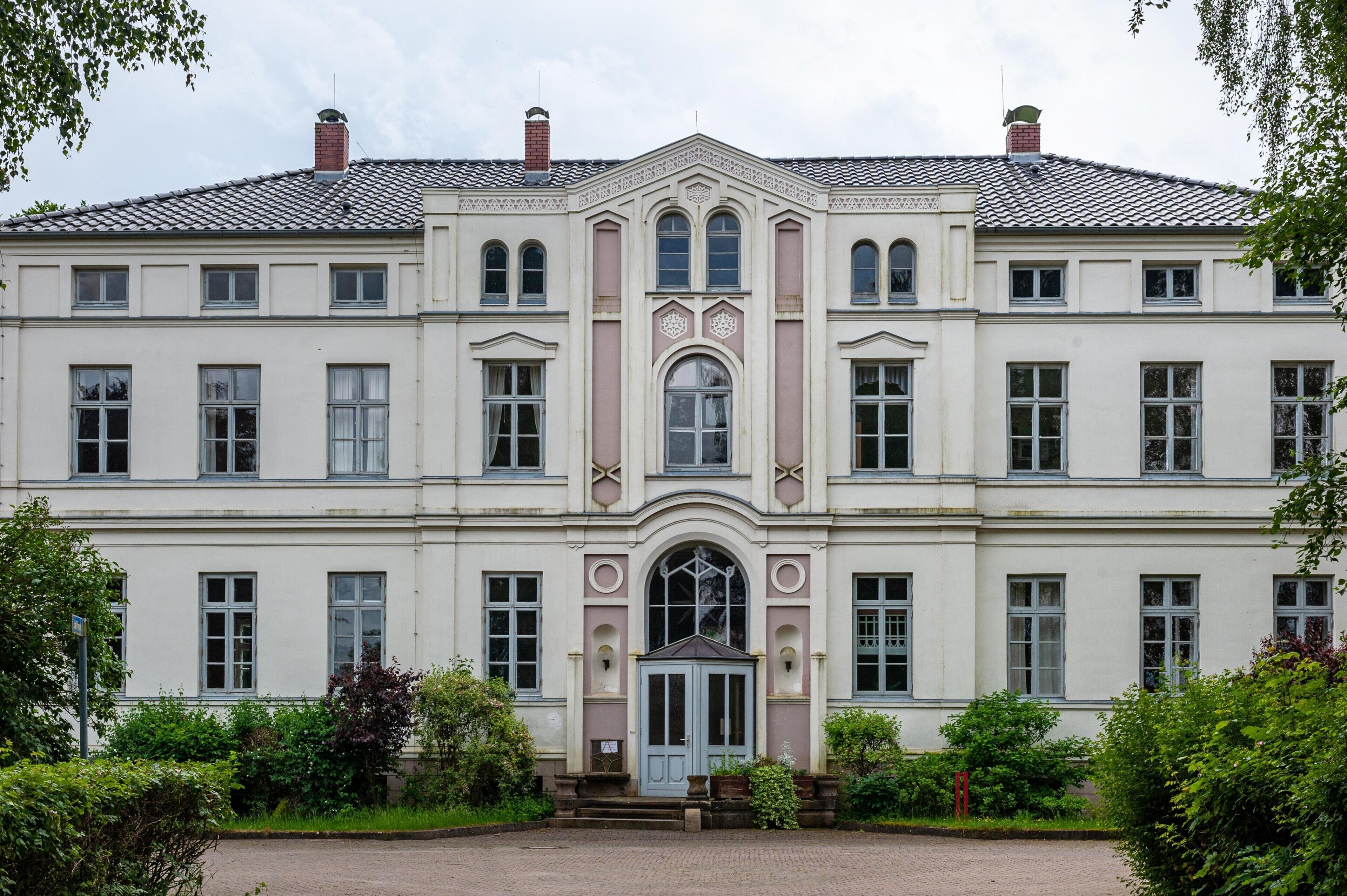 Un grand bâtiment symétrique, doté d’une entrée centrale, de nombreuses fenêtres et d’un toit recouvert de tuiles.