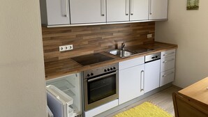 Een moderne keuken met witte kastjes, een houten aanrecht, een inbouwoven en een vaatwasser.