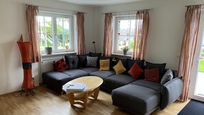 Een moderne woonkamer met een hoekbank, een houten salontafel en een hoge vloerlamp.