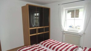 Een slaapkamer met een bed, een kledingkast, een raam met gordijnen en een radiator.