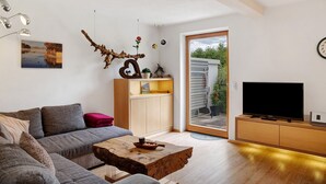 Una sala de estar moderna con un sofá, una mesa de centro, un televisor y un mueble de madera.