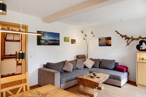 A modern living room with a grey sofa, wooden coffee table, and artwork on the walls.