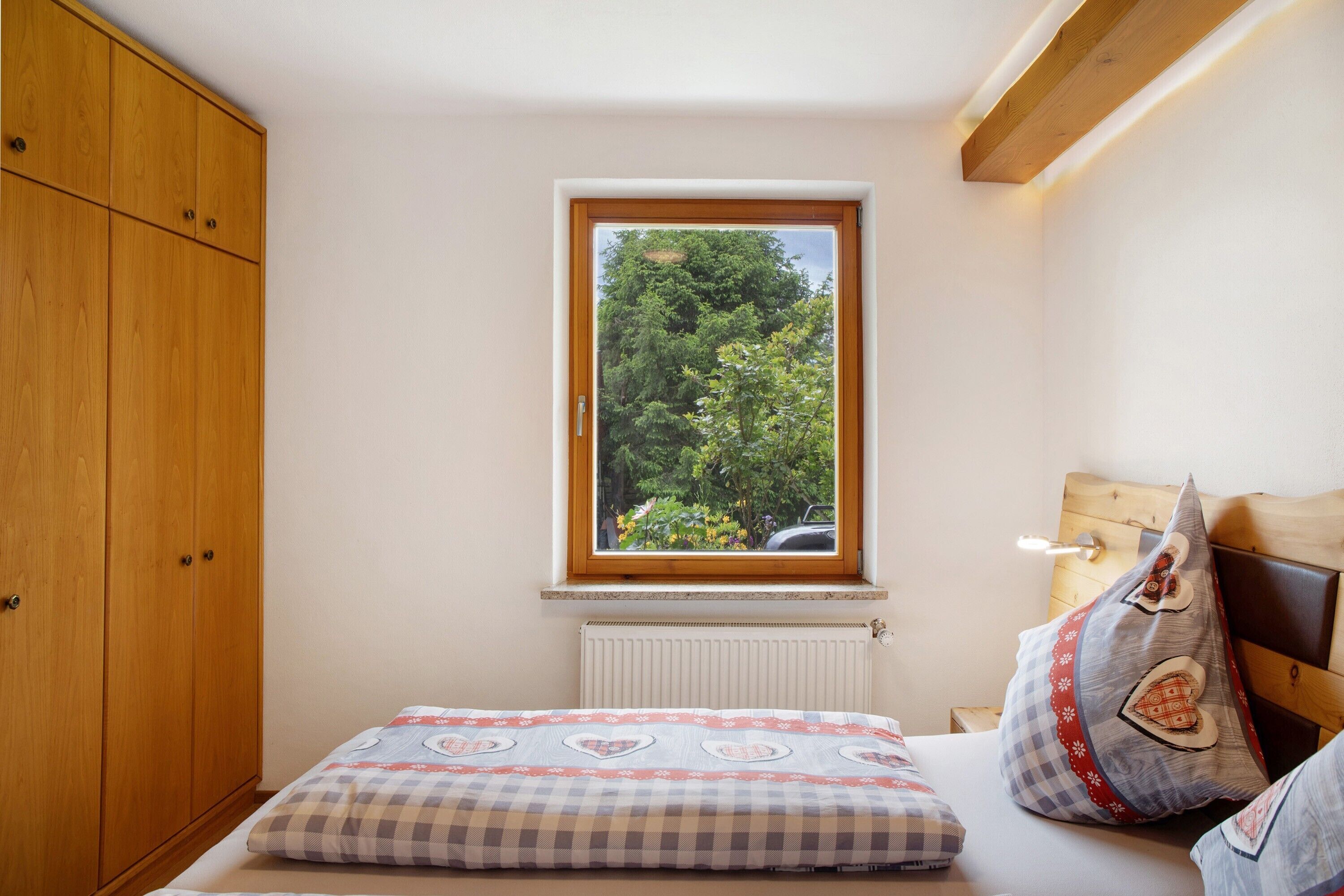 Quarto com janela, cama, guarda-roupa e radiador.