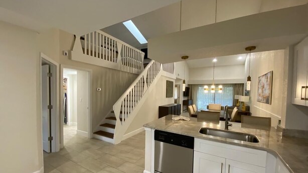 A spacious kitchen with a dishwasher, a dining area with a chandelier, and a staircase leading to an upper level. - Westgate Town Centre Resort (Kissimmee)