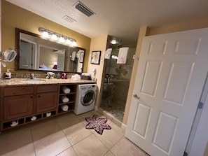 A bathroom with a large mirror, a sink, a washing machine, and a shower area. - Westgate Town Centre Resort (Kissimmee)