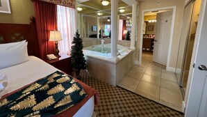 A hotel room with a bed, a bathroom with a bathtub, and a small Christmas tree. - Westgate Town Centre Resort (Kissimmee)