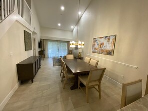 A spacious dining area with a long table and chairs, a dark console table, and a painting on the wall. - Westgate Town Centre Resort (Kissimmee)