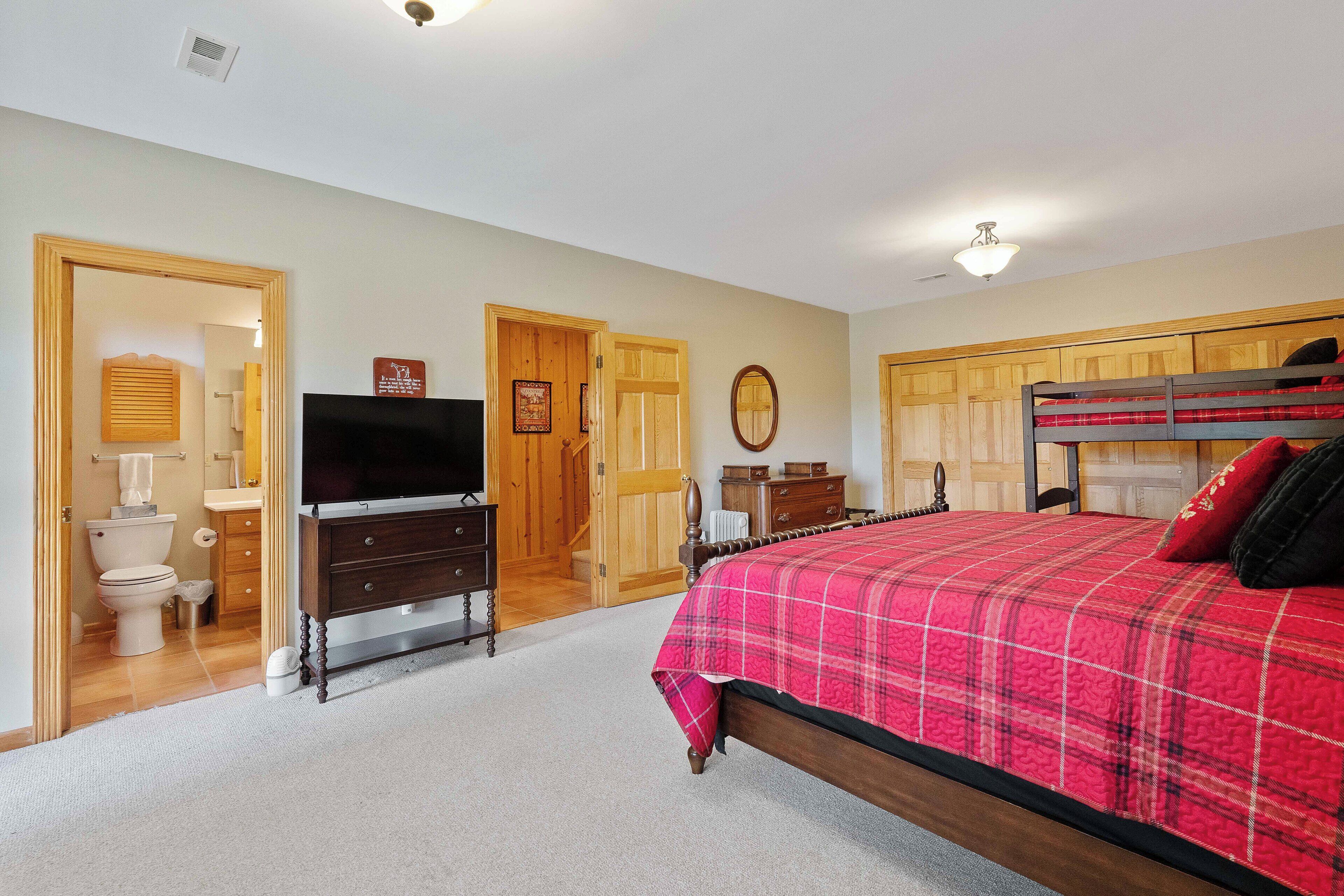 A bedroom with a bed, a dresser, a television, and a wooden wardrobe.