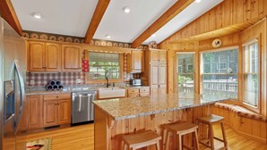 A kitchen with wooden cabinets, granite countertops, and a central island with stools.