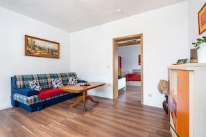 Una sala de estar con un sofá, una mesa de centro de madera y un cuadro en la pared.