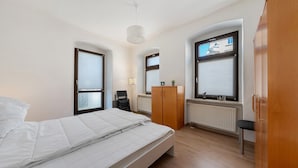 Una camera da letto con un letto, due finestre, un termosifone, un armadio e una scrivania.