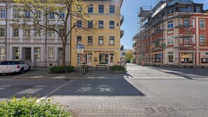 Una strada con edifici, un'auto parcheggiata e un albero.