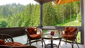 A room with a glass wall, wicker furniture, and a table with a decorative item.