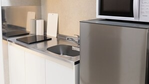 A modern kitchen with stainless steel appliances, a microwave, and a kettle on the countertop.