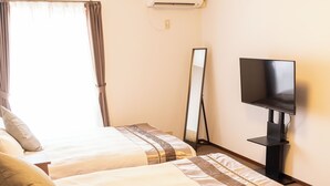 A hotel room with two beds, a TV, a mirror, and a table.
