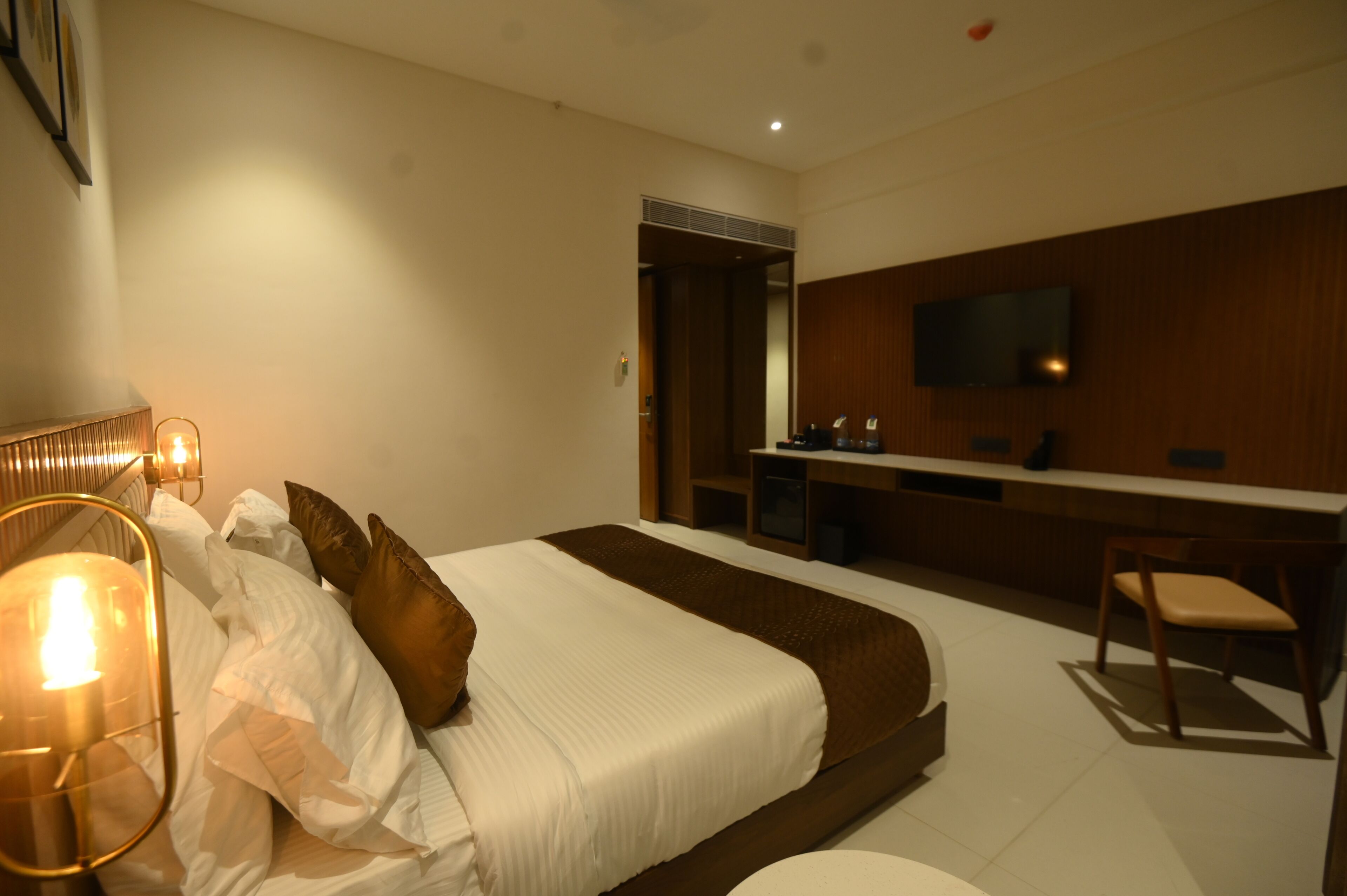 A modern hotel room with a large bed, a desk, and a TV.