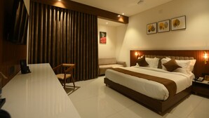 A modern hotel room with a large bed, a desk, and a seating area.
