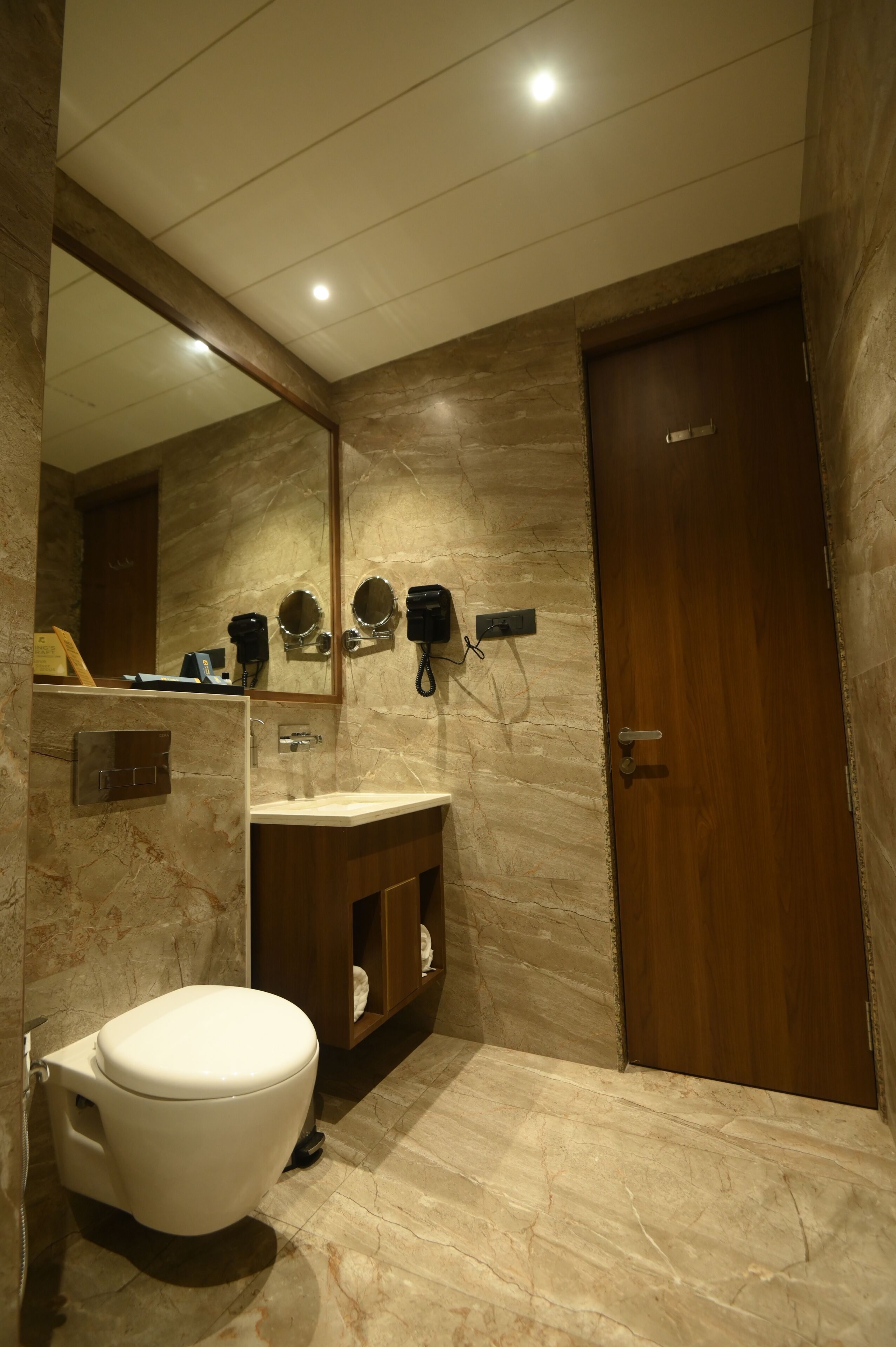 Un baño con inodoro, lavabo, espejo y secador de pelo fijado en la pared.