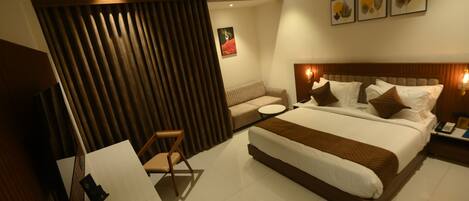 A modern hotel room with a large bed, a sofa, a small table, and a chair.