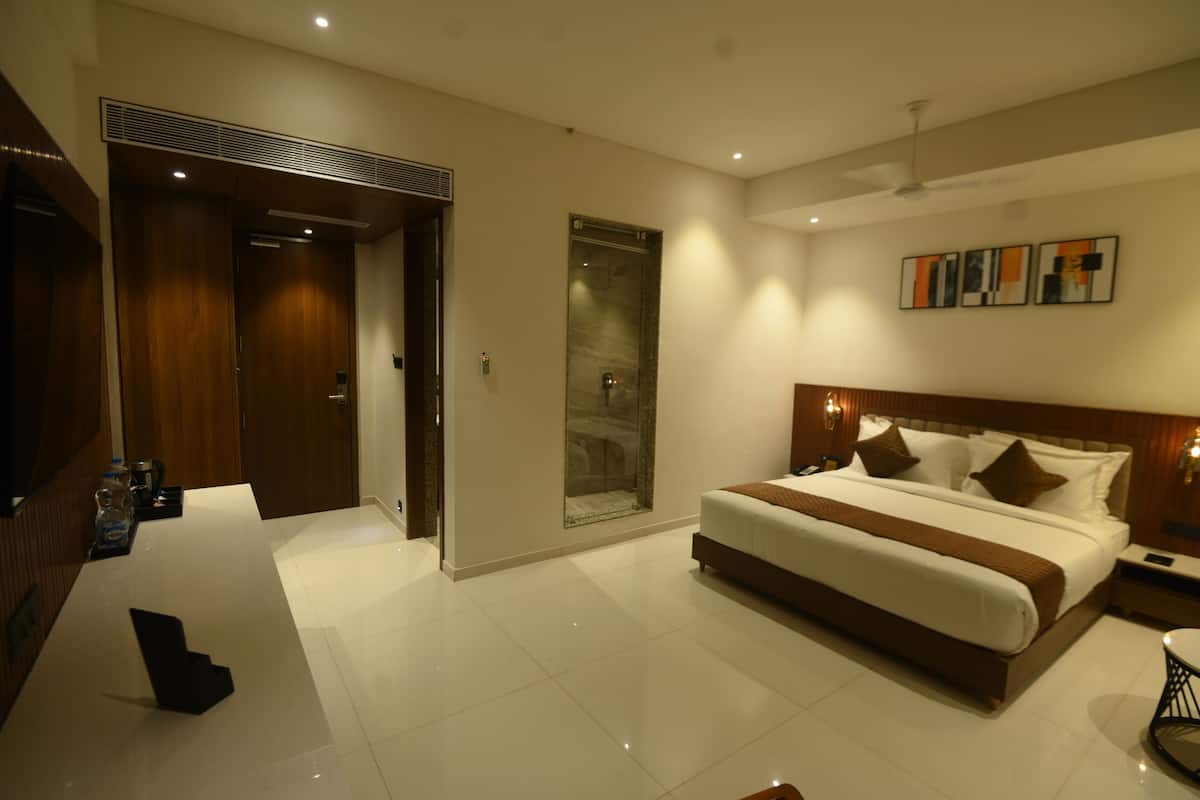 A modern hotel room with a large bed, a desk, and a walk-in closet.