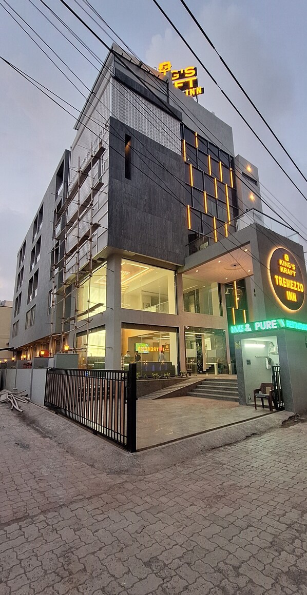 A modern building with a sign for 'King's Kraft Tremezzo Inn' and 'Oms & Pure Restaurant'. - Kings Kraft Tremezzo Inn Somnath (Veraval)